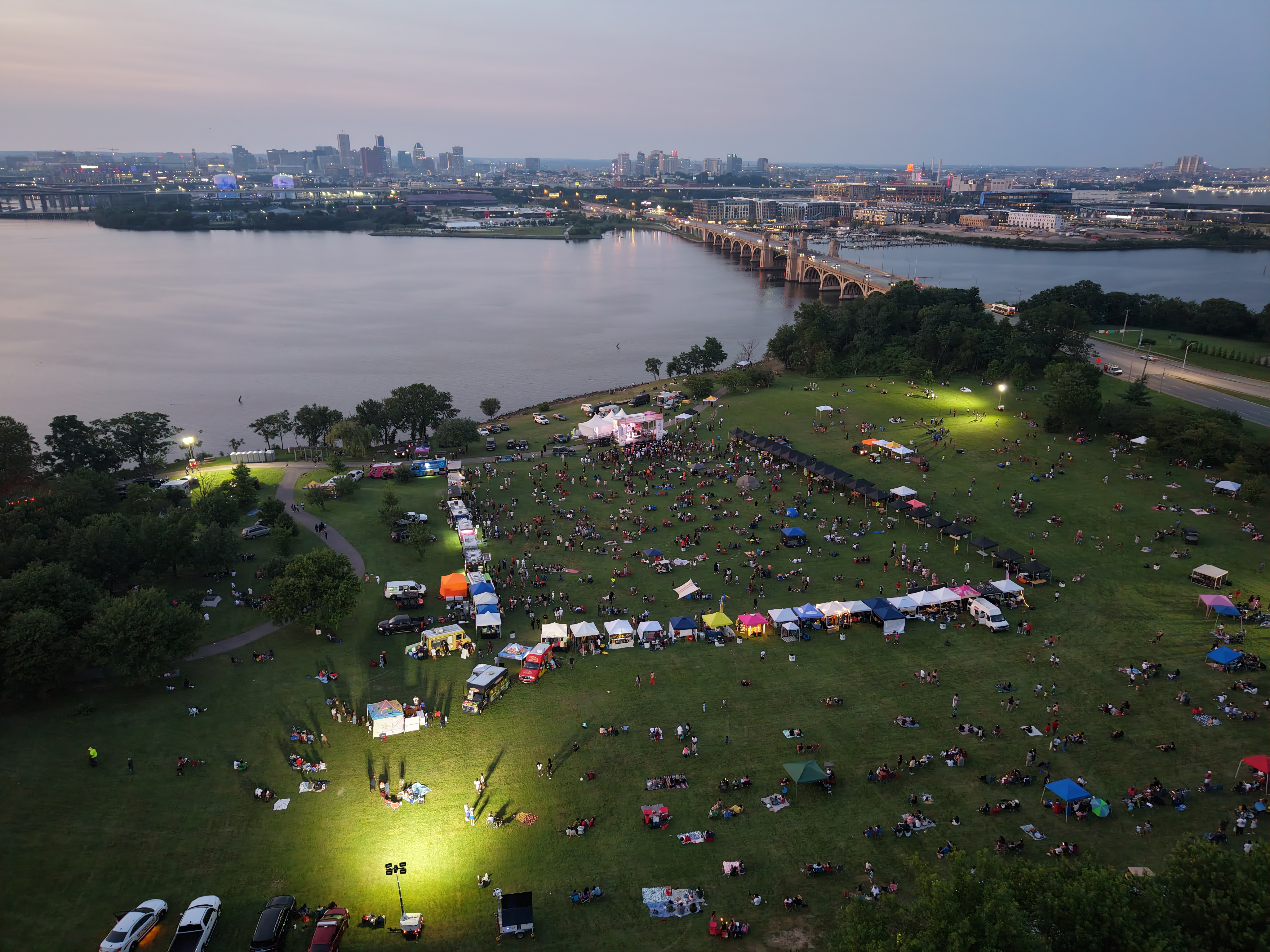 Aerial drone shot of Cherry Hill Arts & Music Waterfront Festival at dusk with Baltimore skyline